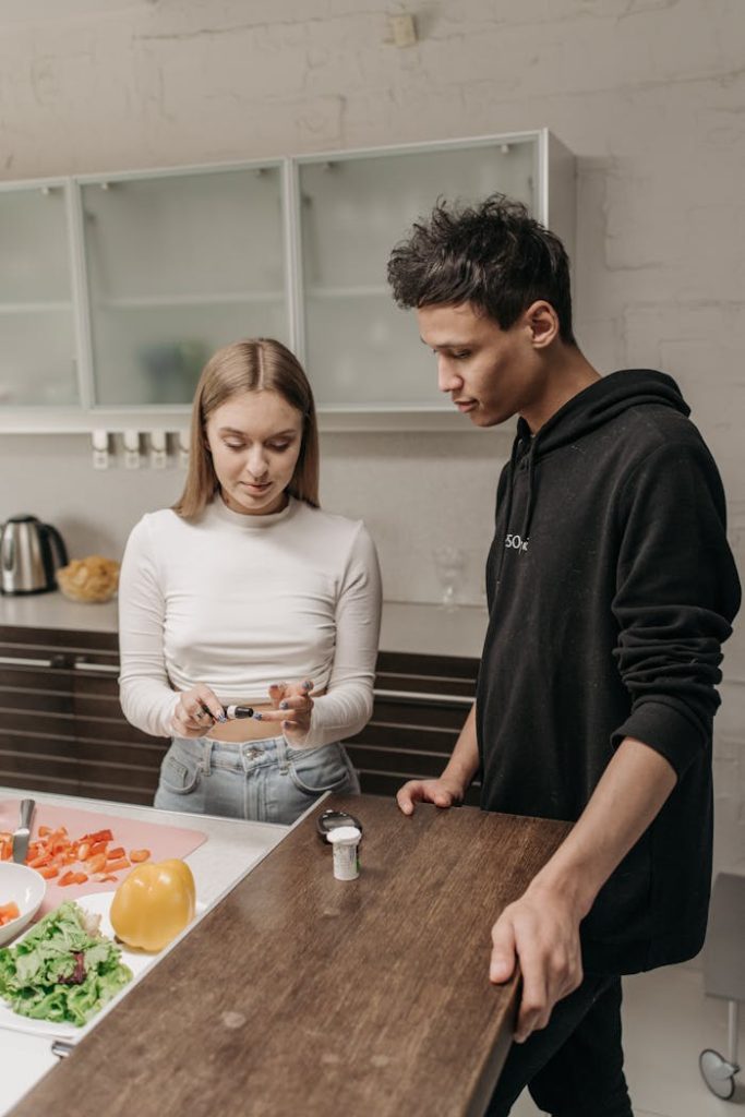 Young couple in kitchen monitoring blood sugar, showcasing life with diabetes.